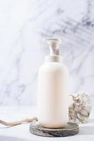 uma cena minimalista de um pódio e garrafa dispensadora branca com pedras em fundo branco, para cosméticos naturais foto