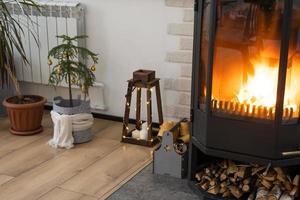 interior festivo da casa é decorado para o natal e ano novo em estilo loft com fogão preto, lareira, árvore de natal. sala de estúdio quente com mesa posta, queima de madeira, aconchegante e aquecimento de casa foto