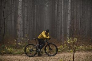 jovem pegando um freio durante o ciclismo pela floresta de outono foto