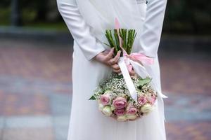 a noiva em um vestido de noiva branco está segurando um buquê de flores brancas - peônias, rosas. Casamento. noiva e noivo. delicado buquê de boas-vindas. bela decoração de casamentos com folhas foto