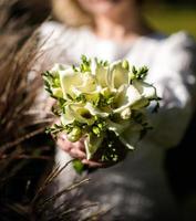 a noiva em um vestido de noiva branco está segurando um buquê de flores brancas - peônias, rosas. Casamento. noiva e noivo. delicado buquê de boas-vindas. bela decoração de casamentos com folhas foto