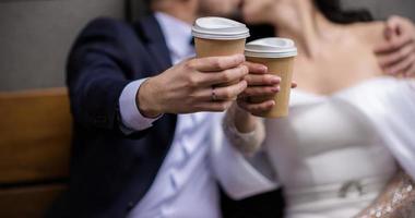 mãos da noiva e do noivo com anéis. noiva e noivo em um café. mesa de buquê de casamento. noiva e noivo seguram as mãos um do outro. alianças de casamento. casal apaixonado em um café. chá quente para os amantes foto