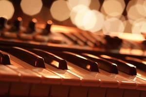 um piano é visto em um cenário bonito e romântico. a foto é uma macro que captura os detalhes intrincados das teclas do piano e o bokeh dourado das luzes de fundo.