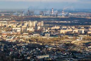 ariel vista panorâmica da cidade com enorme fábrica com chaminés fumegantes ao fundo foto