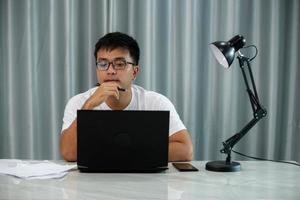 homem freelance asiático sorridente trabalhando no laptop no espaço do saguão do escritório moderno. jovem estudante indiano usando computador remoto estudando, assistindo webinar online, treinamento virtual em videochamada foto