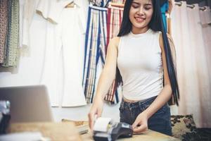 caixa no trabalho. caixa jovem atraente passa um cartão de plástico através de uma máquina e sorrindo foto