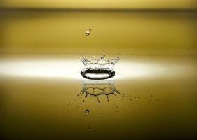respingo de água com reflexo e gotas sobre um fundo amarelo foto