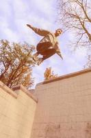 um jovem dá um salto pelo espaço entre os parapeitos de concreto. o atleta pratica parkour, treinando em condições de rua. o conceito de subculturas esportivas entre os jovens foto