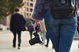 vista traseira de uma garota com uma câmera digital em uma rua lotada ba foto