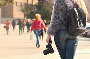 vista traseira de uma garota com uma câmera digital em uma rua lotada ba foto