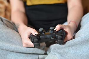 uma jovem joga videogame com um joystick preto com muitos b foto
