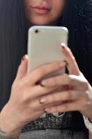 a menina morena usa um smartphone de toque moderno foto