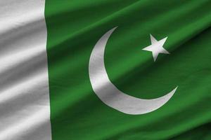 bandeira do paquistão com grandes dobras acenando perto sob a luz do estúdio dentro de casa. os símbolos e cores oficiais no banner foto