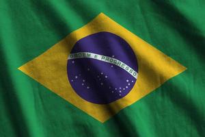 bandeira do brasil com grandes dobras acenando perto sob a luz do estúdio dentro de casa. os símbolos e cores oficiais no banner foto
