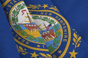 bandeira do estado de New Hampshire nos EUA com grandes dobras acenando de perto sob a luz do estúdio dentro de casa. os símbolos oficiais e cores no banner foto
