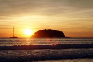 a vista panorâmica sobre o mar com um pequeno barco e ilha durante o pôr do sol. Phuket, Tailândia. foto