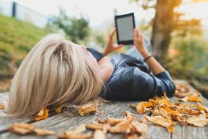 menina loira lê um livro de seus leitores de ebooks foto