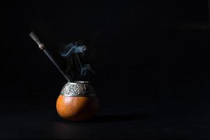 bebida de erva-mate de chá quente com fumaça em fundo preto foto