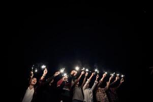 grupo de jovens amigos segurando e brincando com estrelinhas de fogo foto