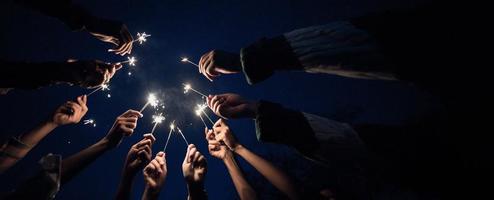 grupo de jovens amigos se divertem com fogos de artifício nas mãos juntos foto