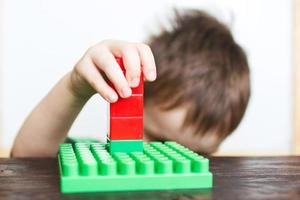 menino criança brincando com construtor de plástico foto