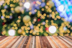 tampo de mesa de madeira vazio com árvore de natal desfocada com fundo claro bokeh foto