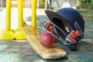 equipamento de críquete é uma bola de críquete, taco de críquete, capacete de críquete em um fundo de grama. foco suave e seletivo. foto