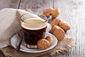 café preto em um copo com biscoitos de amêndoa foto