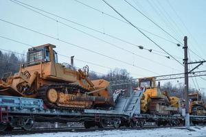 tratores pesados de mineração em plataformas ferroviárias de carga aberta. foto