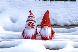 cartão de férias de natal gnomos escandinavos fofos com chapéu vermelho e barba branca no banco de inverno nevado conto de fadas queda de neve inverno olá dezembro, janeiro, conceito de fevereiro feliz ano novo, natal foto