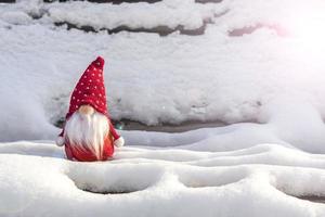 cartão de férias de natal gnomos escandinavos fofos com chapéu vermelho e barba branca no banco de inverno nevado conto de fadas queda de neve inverno olá dezembro, janeiro, conceito de fevereiro feliz ano novo, natal foto