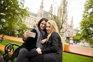 jovens turistas femininas tirando selfie com foto móvel no centro de viena, áustria