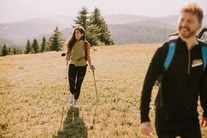 casal sorridente caminhando com mochilas pelas colinas verdes foto