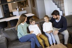 jovem família assistindo tv juntos no sofá da sala foto