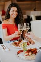 jovem casal almoçando com vinho branco no restaurante foto