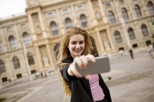 jovem turista feminina tirando selfie com foto móvel no centro de Viena, Áustria