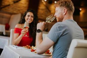 jovem casal almoçando com vinho branco no restaurante foto