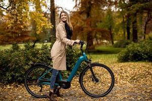 jovem mulher com bicicleta elétrica no parque de outono foto