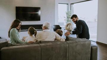 família de várias gerações sentada no sofá em casa e assistindo tv foto