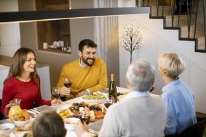 família feliz jantando com vinho tinto em casa foto