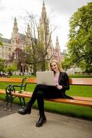 jovem mulher com laptop no banco do parque foto