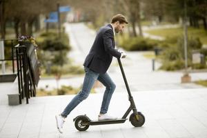 jovem empresário andando de scooter elétrico foto