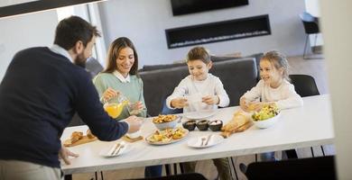 jovem família feliz conversando enquanto toma café da manhã na mesa de jantar foto