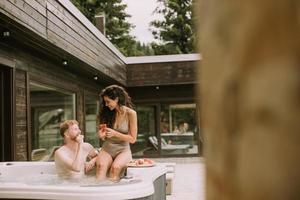 jovem casal desfrutando na banheira de hidromassagem ao ar livre de férias foto