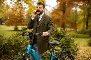 jovem com bicicleta elétrica no parque outono foto