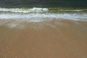 ondas na costa da bela praia de areia tropical em um dia ensolarado foto