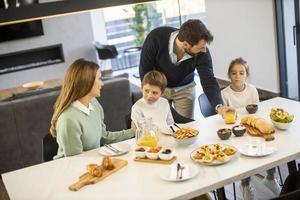 jovem família feliz conversando enquanto toma café da manhã na mesa de jantar foto