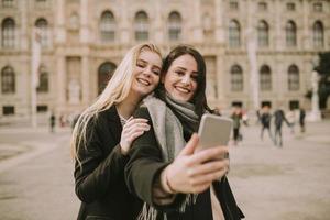 jovens turistas femininas tirando selfie com foto móvel no centro de viena, áustria