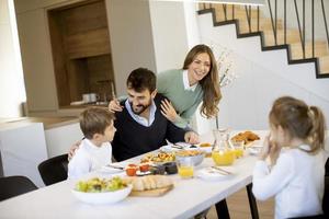jovem família feliz conversando enquanto toma café da manhã na mesa de jantar foto