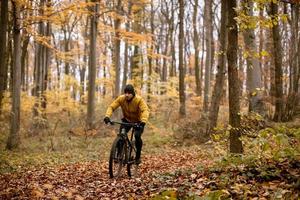 jovem andando de bicicleta pela floresta de outono foto